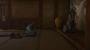 Inoshichi sitting infront of his samurai armor on display